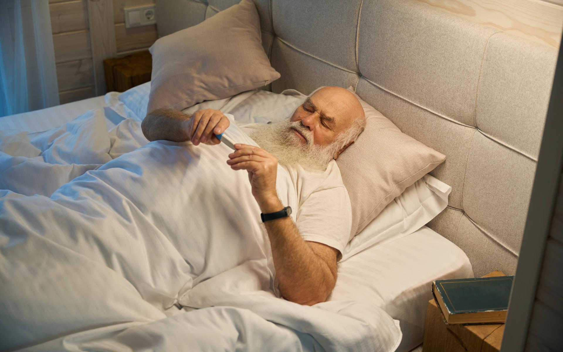 Älterer Mann mit Pflegegrad 5 liegt im Bett