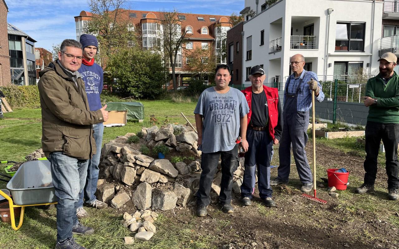 Boris Pohlen (links) und Teilnehmer des LV-Projektes beim Bau der Kräuterspirale im Gemeinschaftsgarten der Katholischen Kirche Grevenbroich.  Foto: Caritas Rhein-Kreis Neuss - Abdruck honorarfrei