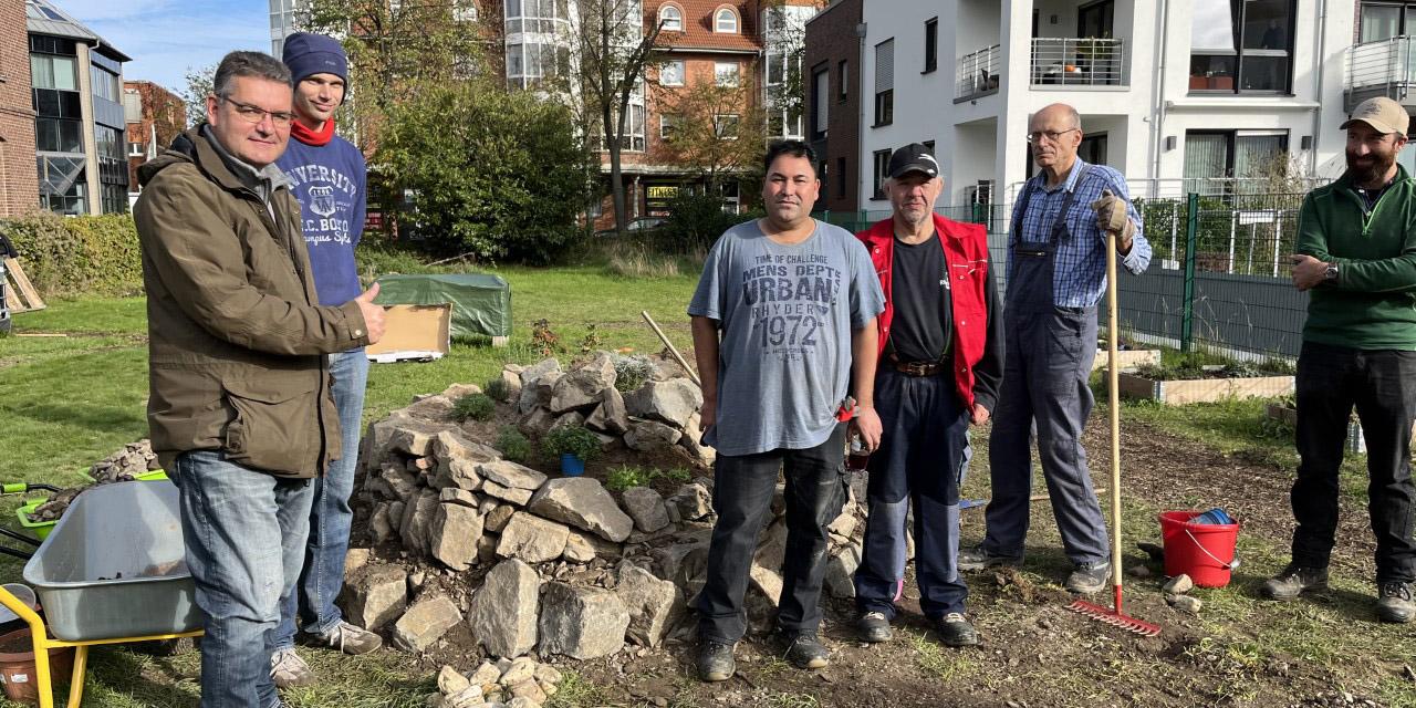 Boris Pohlen (links) und Teilnehmer des LV-Projektes beim Bau der Kräuterspirale im Gemeinschaftsgarten der Katholischen Kirche Grevenbroich. Foto: Caritas Rhein-Kreis Neuss - Abdruck honorarfrei
