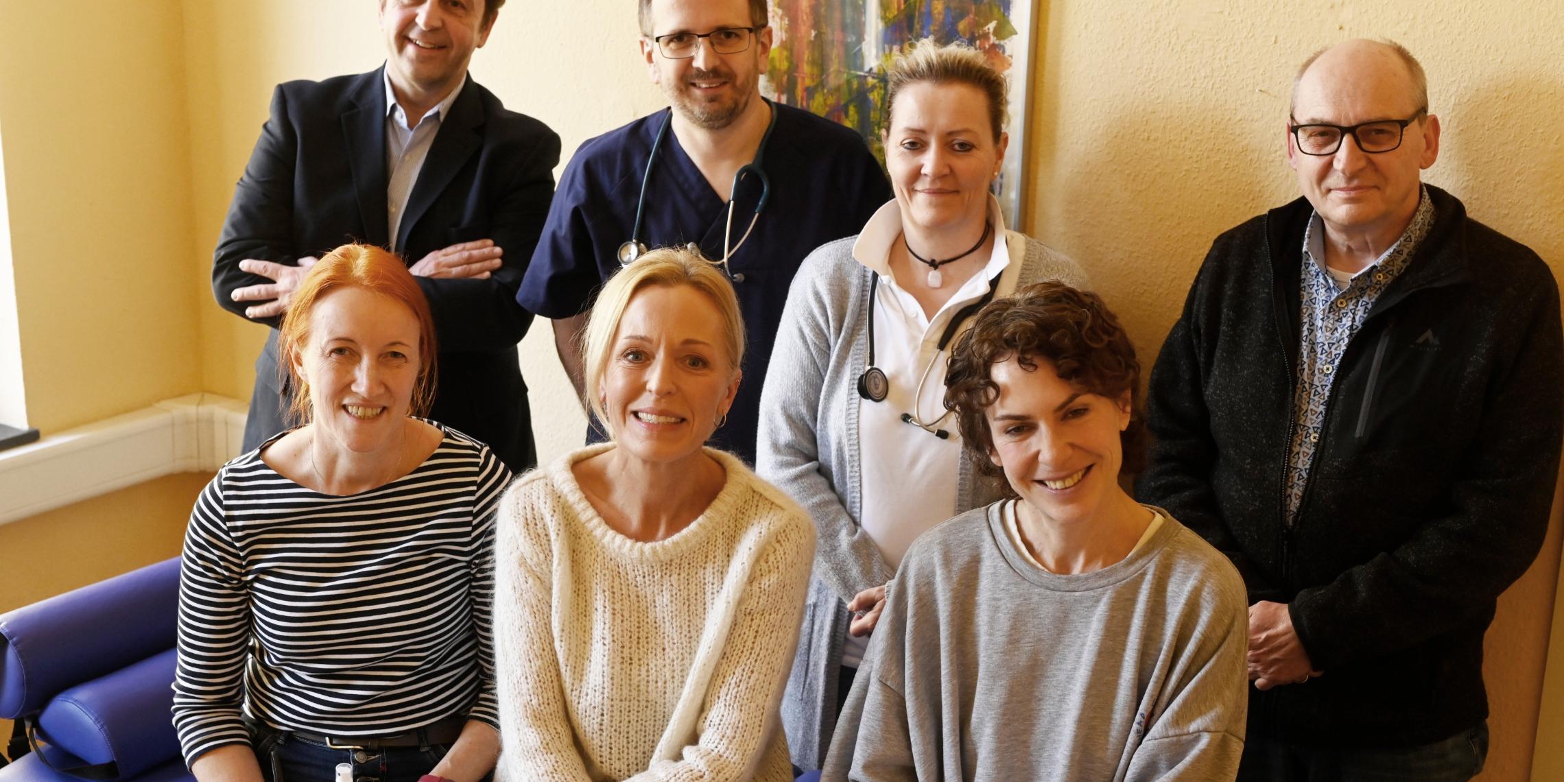 Im 3. Stock des Café Ausblick stellen das Patientenzimmer vor (sitzend von links): Pflegetherapeutin Uta Wehrmann, Petra Lennertz und Nadja Schloßmacher (beide NEUSS HILFT e.V.); stehend von links: Dirk Jünger (Leitung CaritasSozialdienste Rhein-Kreis Neuss), Robert Bellin (Facharzt für Innere Medizin), Ursula P. Schmitz (Fachärztin für Allgemeinmedizin), Klaus Heidemann (Fachbereichsleitung Wohnungslosen- /Gefährdetenhilfe Nordkreis).